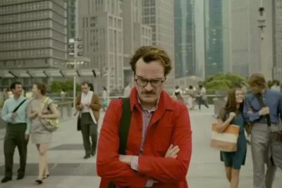 Her filmi Joaquin Phoenix Theodore karakteri kırmızı ceket ve melankolik bakış, fütüristik şehirde yürüyüş